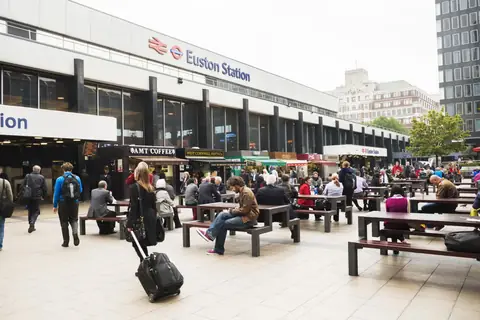 Passengers sitting on the forecourt outside Euston station